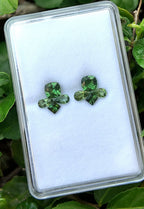 Green clover earrings on a white card with green leaves in the background